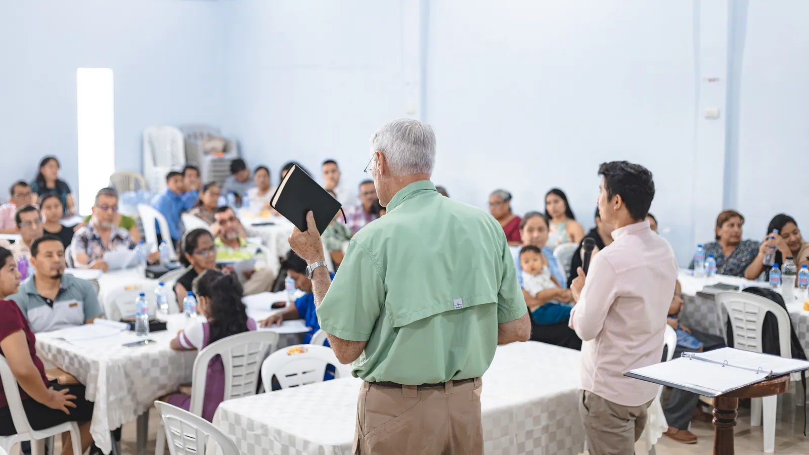 Russell sostiene en alto una Biblia mientras enseña a pastores durante un encuentro de capacitación.
