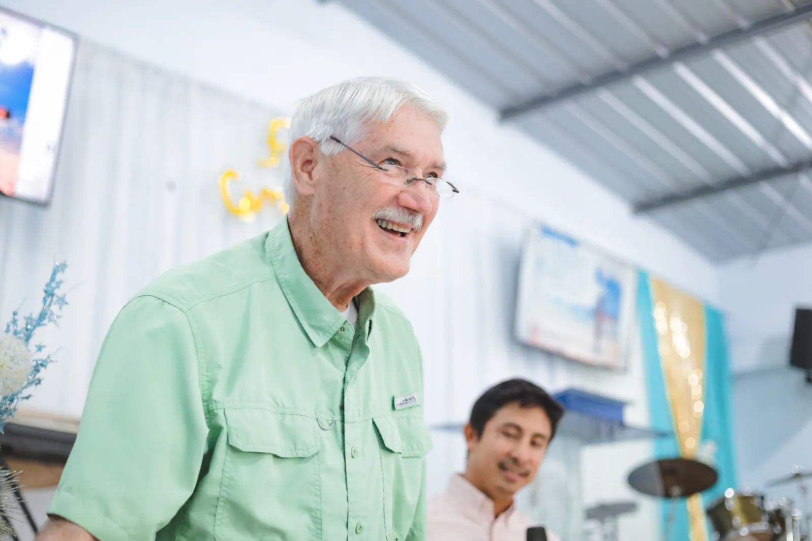 Russell smiling during a ministry gathering, with Israel visible in the background.