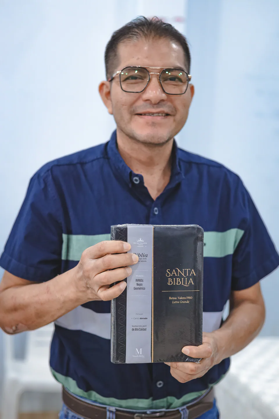 A pastor smiling while holding a Study Bible received for ministry use.